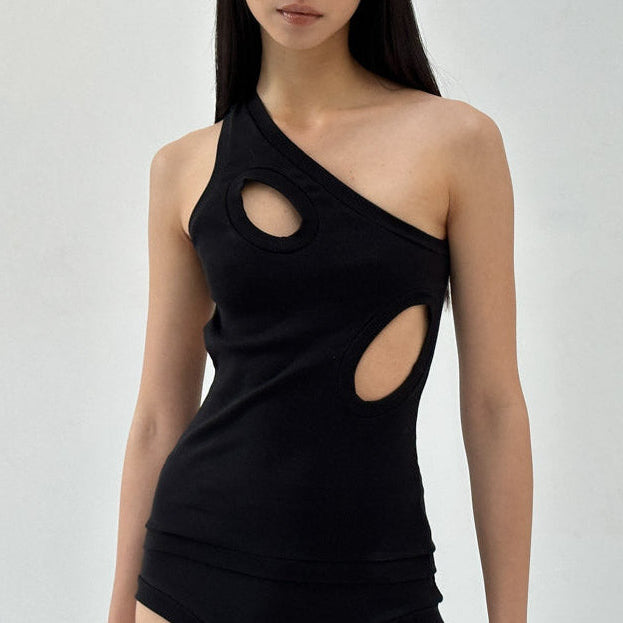 Woman wearing a black one-shoulder top and black high-waisted shorts on a white background